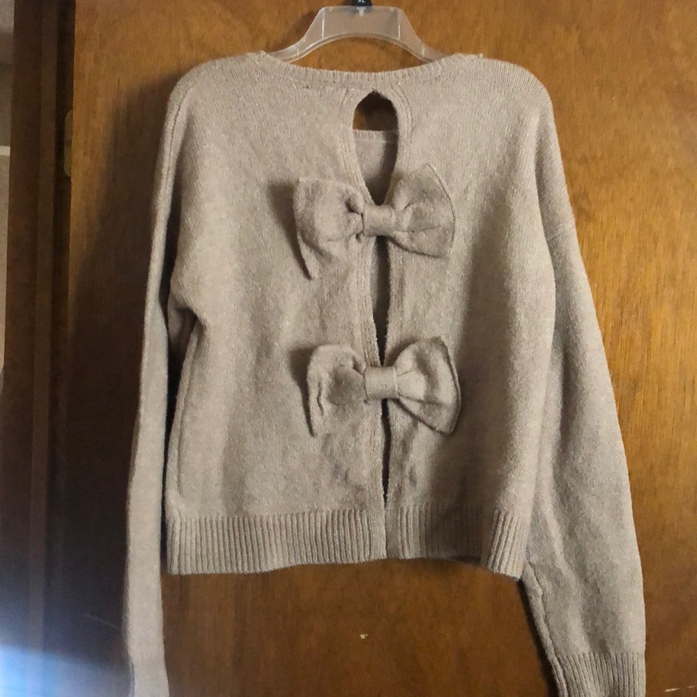 Brown sweater with bow ties on back.